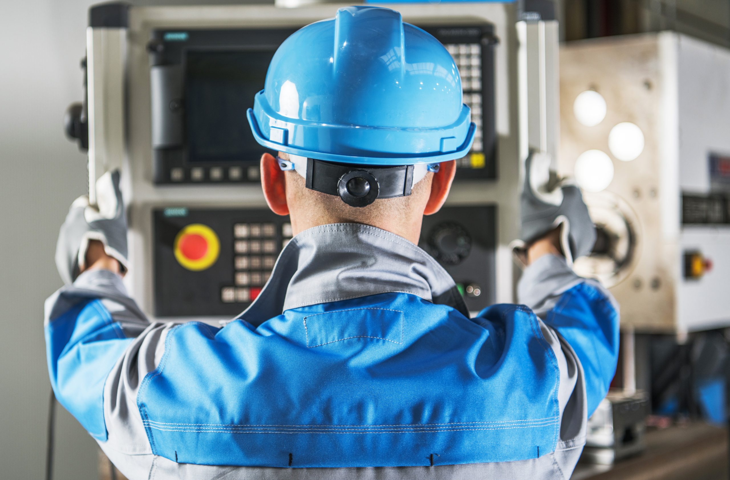 Caucasian CNC Operator in Front of Machine Operating Console. Metalworking Concept.